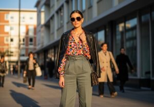 Stylová žena v městském prostředí v barevném outfitu s koženou bundou a slunečními brýlemi