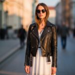 Mladá žena v černé kožené motorce stojí na městské ulici za zlaté hodiny ve městském stylu